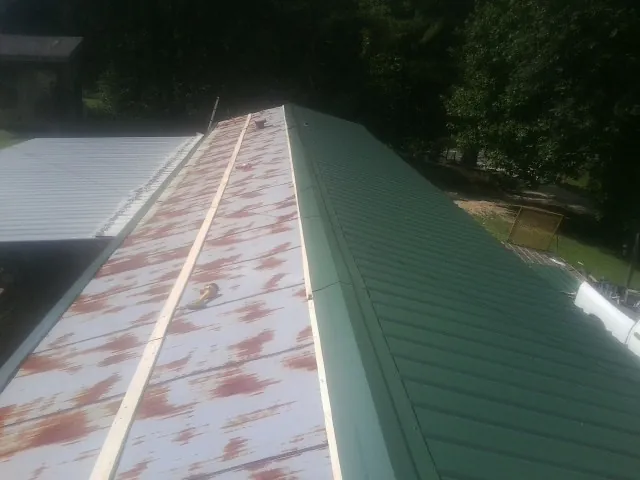 Old rusted panels beside newly installed green metal roofing — Wind Damage Roof Repair by Roofing Brothers in Teton