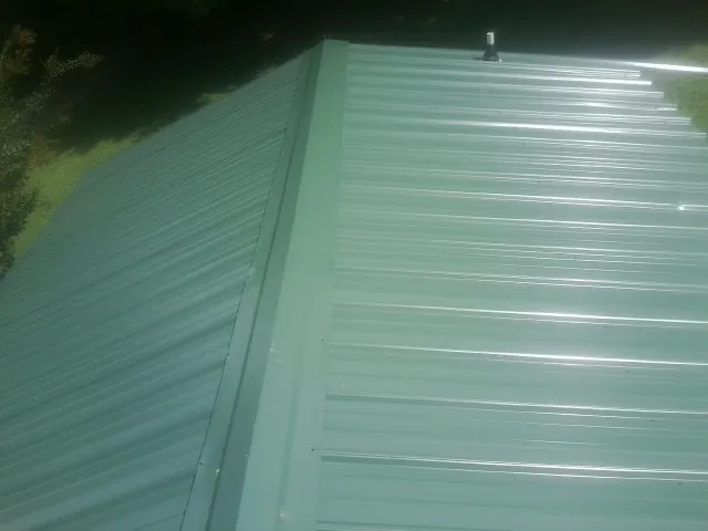 New green metal panels meeting at the ridge of a roof — Flat Roof Repair work by our crew in Teton