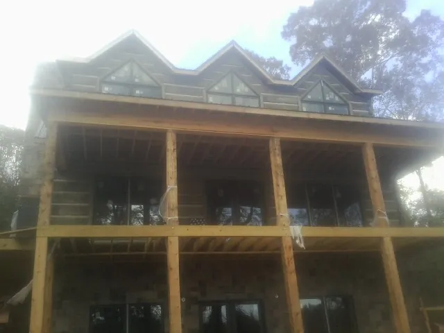 Dormers and porch framing on a large log home under construction — Roof Coating work by our crew in Teton