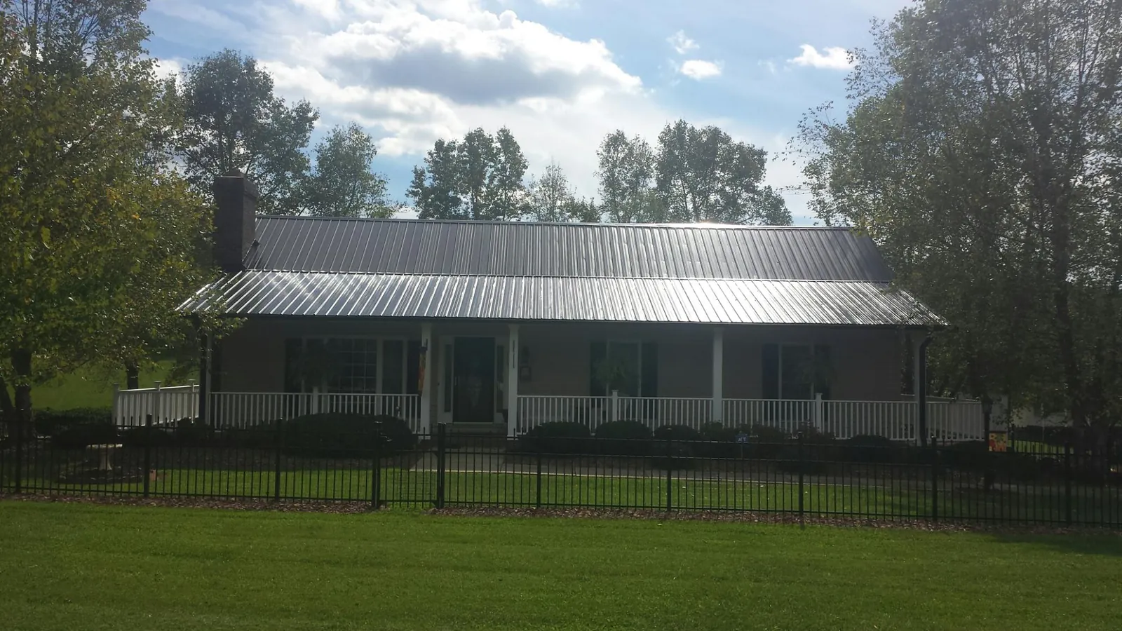 Gray metal roof on a brick ranch with a full width front porch — Gutter Guard Installation work by our crew in Teton