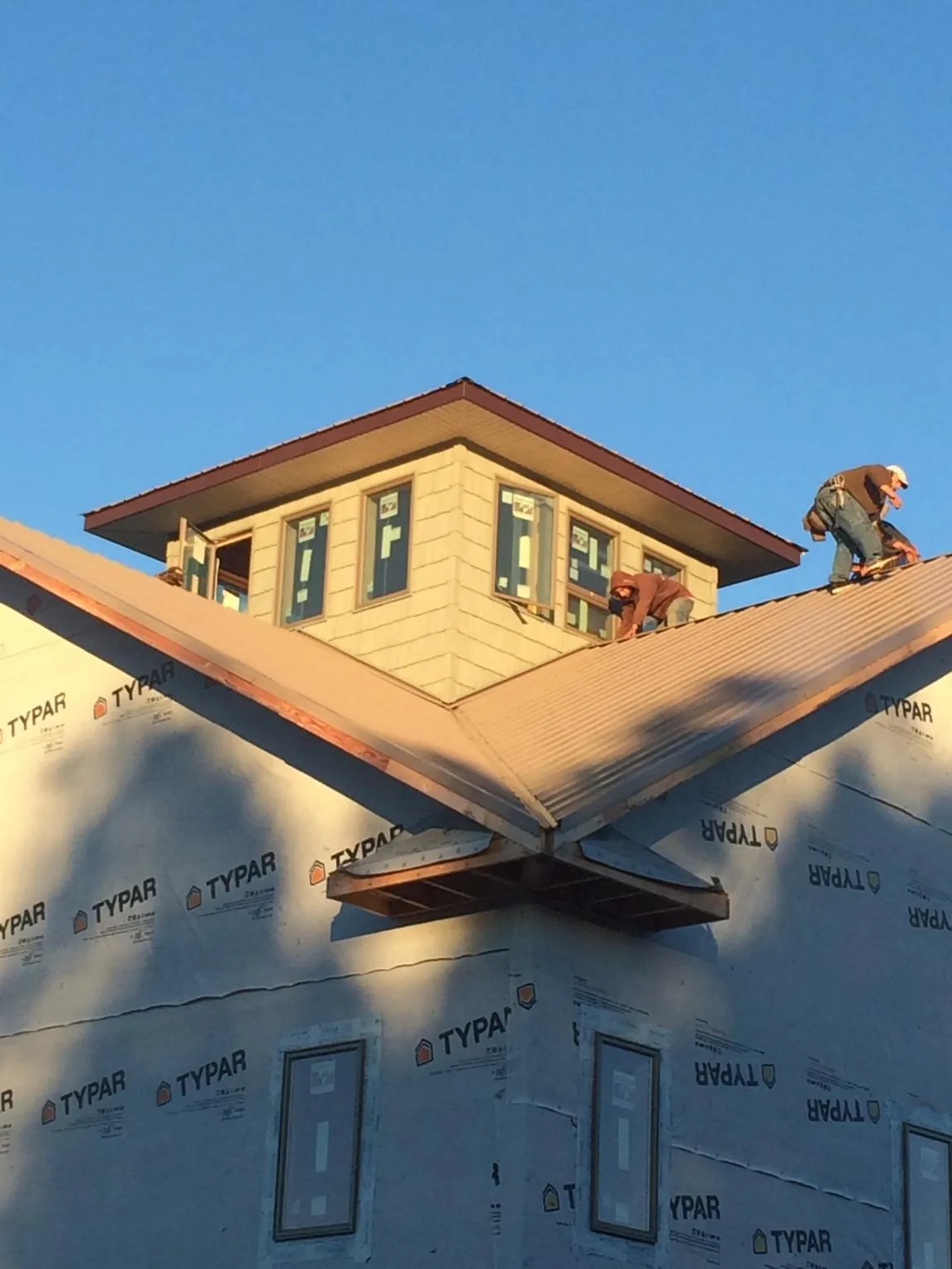 Roofers working around a rooftop cupola on a new metal roof at sunset — Roof Waterproofing in Teton by Roofing Brothers